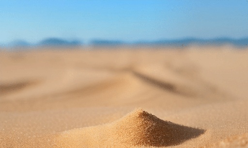 sand on a beach with a blue sky in the background