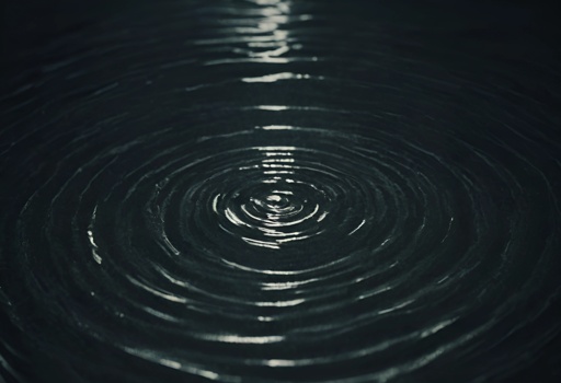 image of a dark water ripple with a light reflecting on it